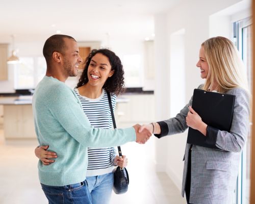 real estate agent shaking hands of a man who is embracing a woman