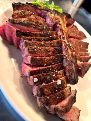 wonderful rare, grilled porterhouse steak on a platter with sea salt