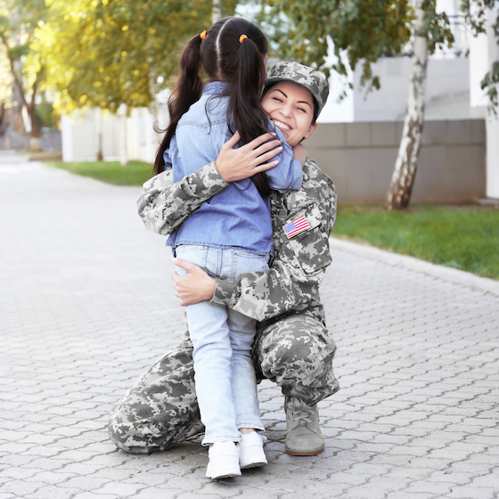 mother in military uniform hugging her daughter