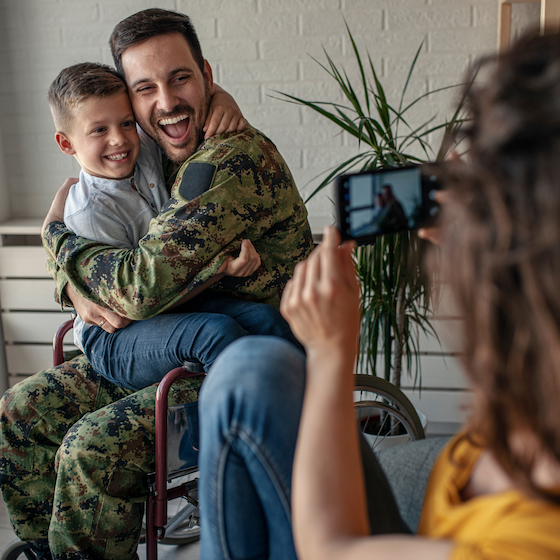 man in combat fatigues in a wheelchair hugging his young son.