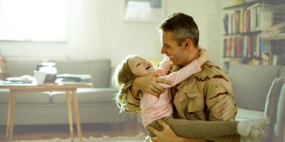 Veteran father holding his young daughter in his arms.